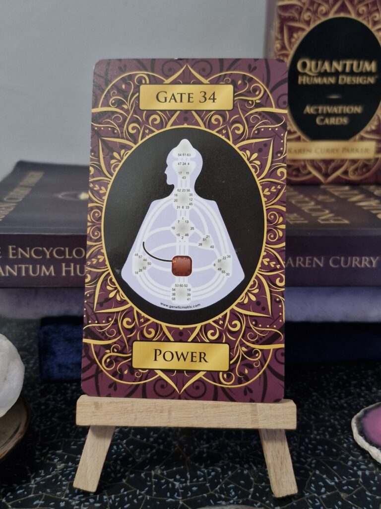 A brown card with the human design bodygraph showing the gate 34 defined. There is a card box in the background with Quantum Human Design cards on it by Karen Curry Parker